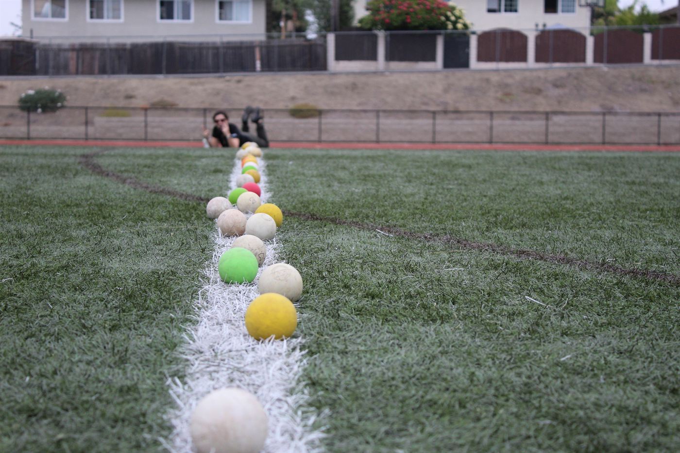 Lacrosse balls lined up along a chalk line on the practice field.